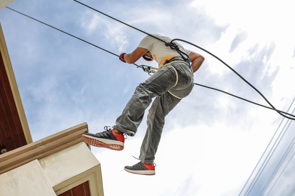 A man rappels down a building, emphasizing safety and skill in outdoor adventure sports.
